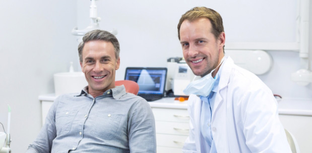 smiling-man-sitting-in-dental-chair-with-dentist