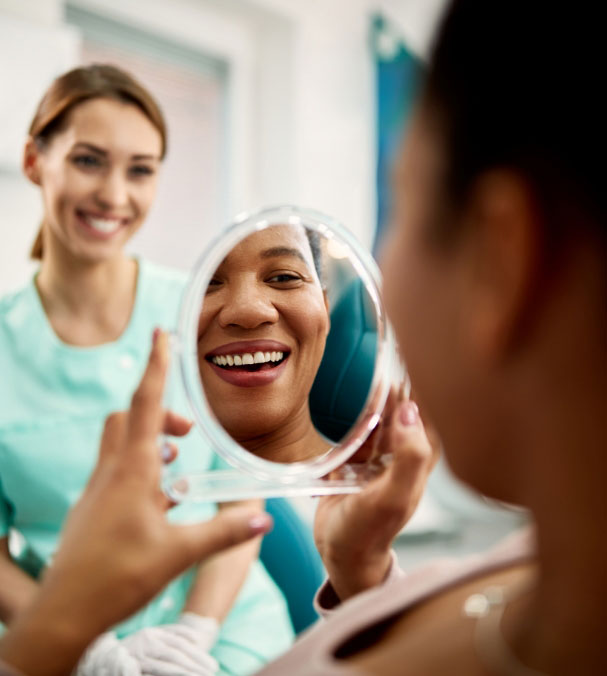 smiling-woman-looking-at-reflection-in-mirror-with-dentist